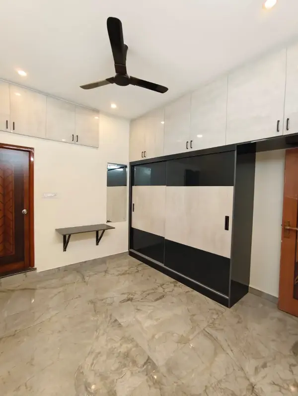 Affordable home interior in Bangalore – bedroom with a black and white sliding wardrobe by Prestige Craft Interiors