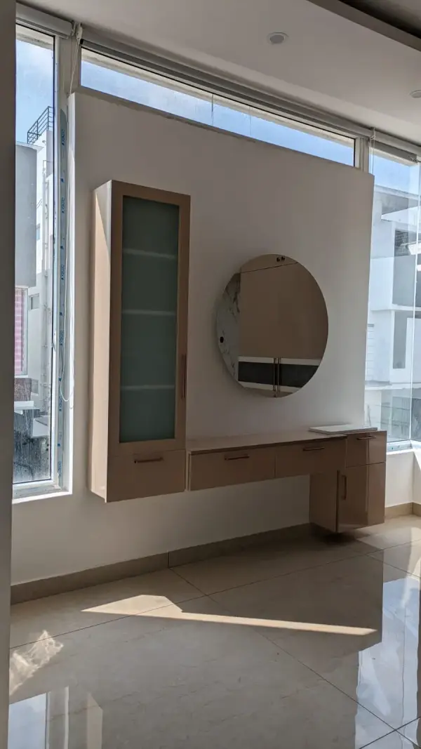 Affordable home interior in Bangalore – dressing unit with round mirror and wall-mounted storage by Prestige Craft Interiors
