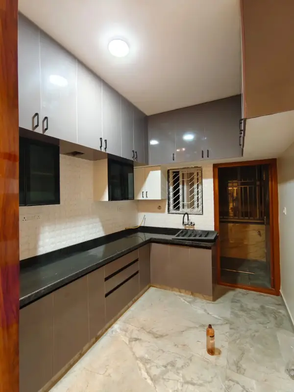Affordable home interior in Bangalore – modular kitchen with grey cabinets and black granite countertop by Prestige Craft Interiors